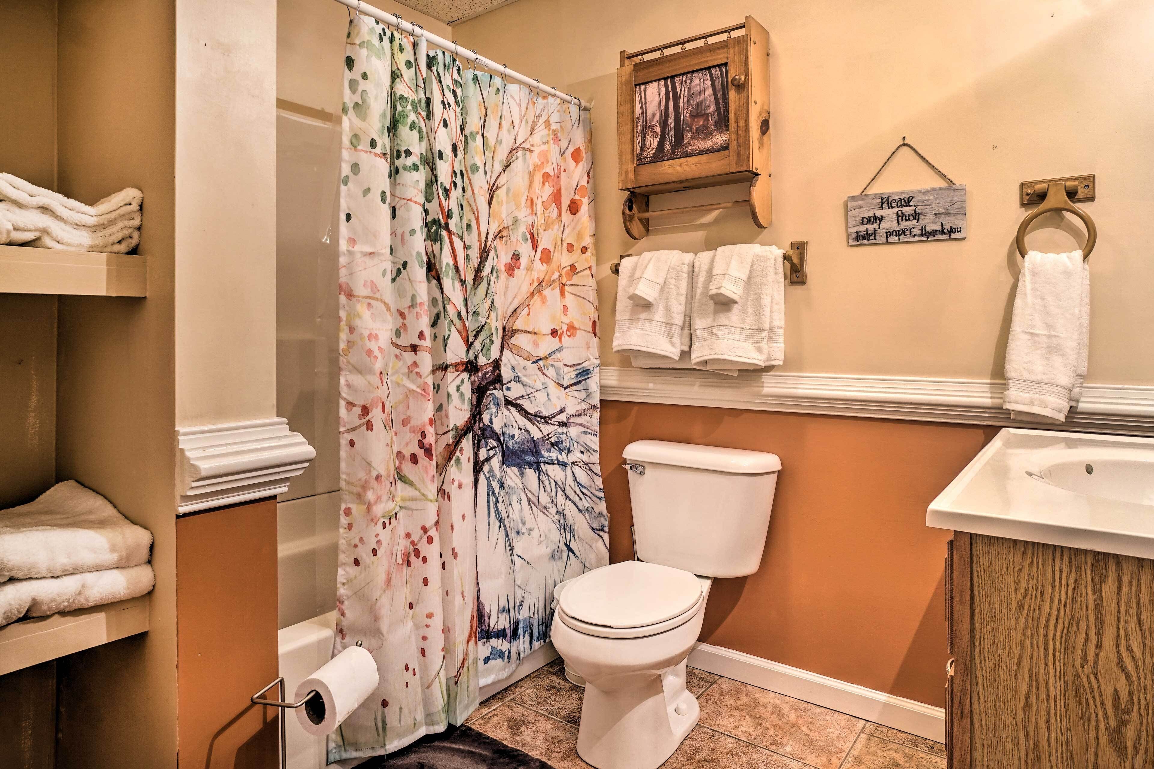Une salle de bain équipée d’un rideau de douche, de toilettes, d’un lavabo et d’un porte-serviettes.