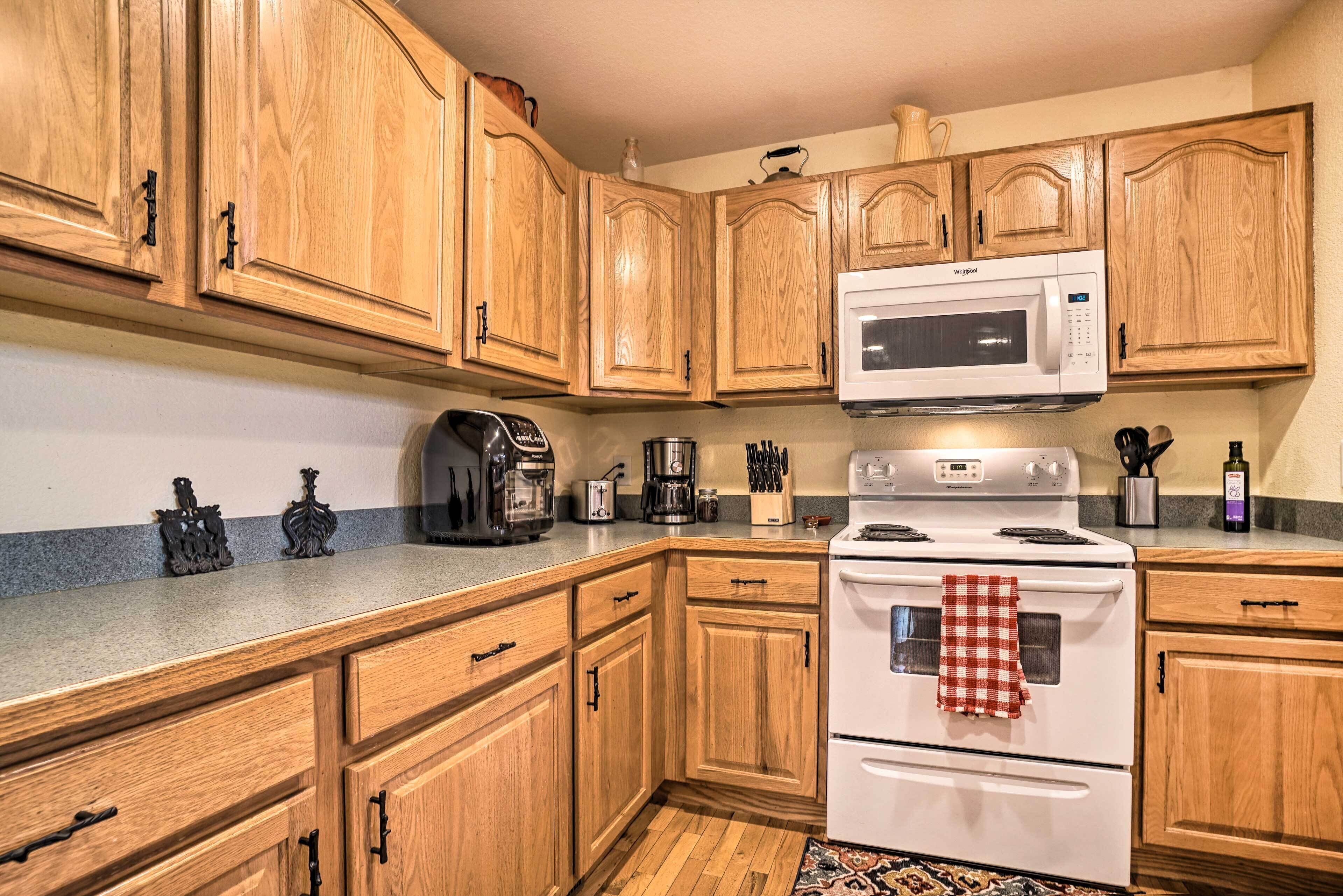 A kitchen with wooden cabinets, a microwave, a coffee maker, a toaster, and a stove.