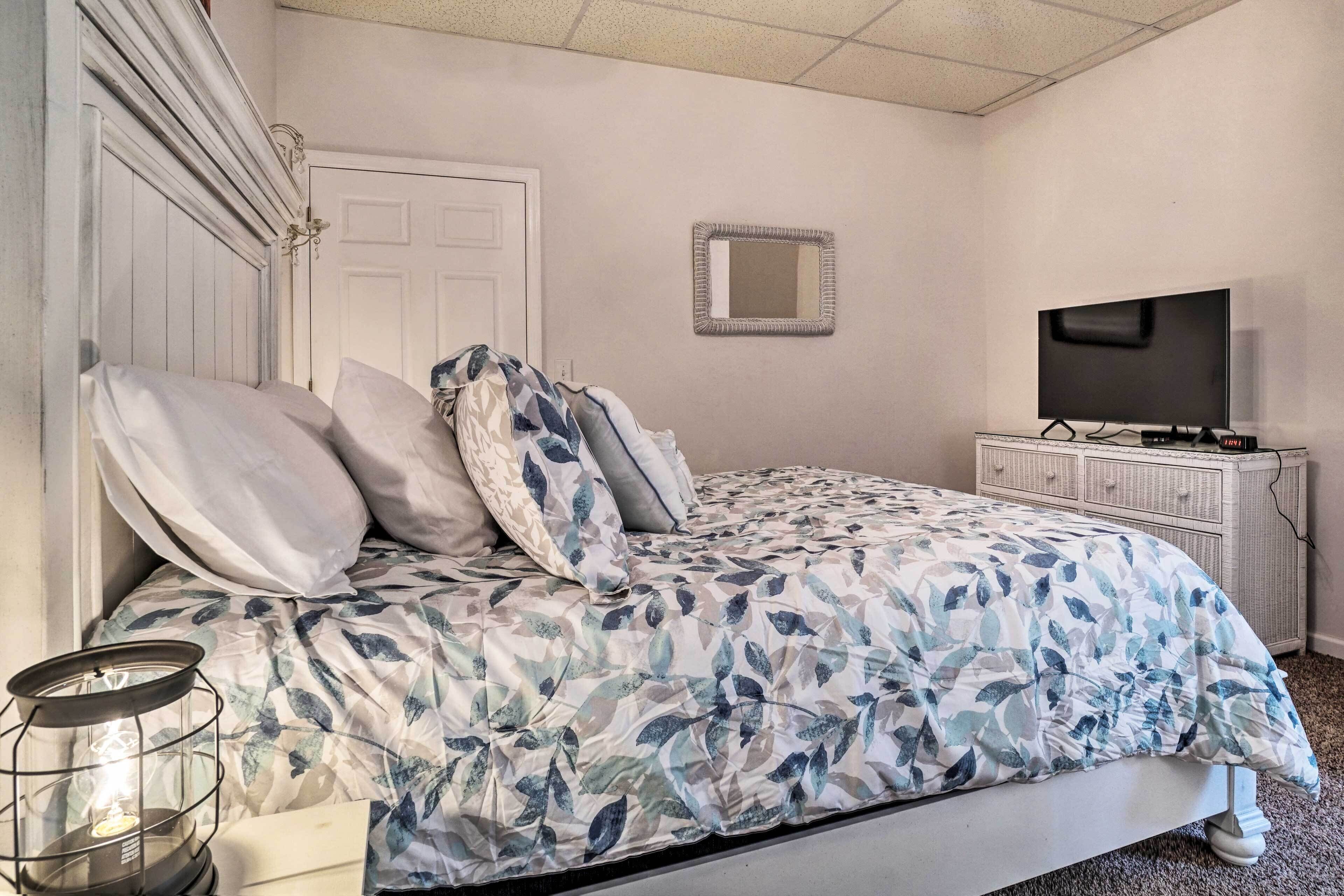Une chambre à coucher avec un lit, une télévision, une commode et un miroir.