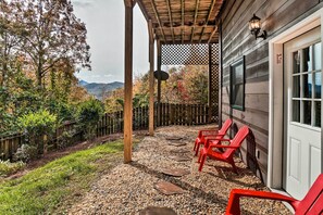 Un portico riparato con poltrone Adirondack rosse, una recinzione in legno e vista sulle montagne.