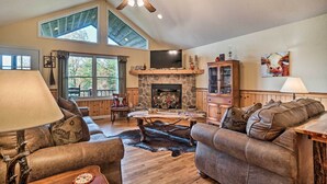 A spacious living room with a stone fireplace, leather sofas, a wooden coffee table, and a ceiling fan. - Hiawassee Cabin w/ Mtn Views < 1 Mi to Lake! (Hiawassee)