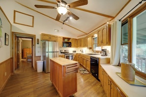 A kitchen with wooden cabinets, a ceiling fan, a refrigerator, a microwave, and a coffee maker.