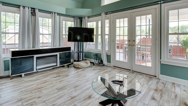 A spacious room with a large window, a television, and a glass table.