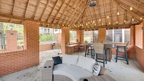 A covered patio area with a brick wall, a curved sofa, and a table with chairs.