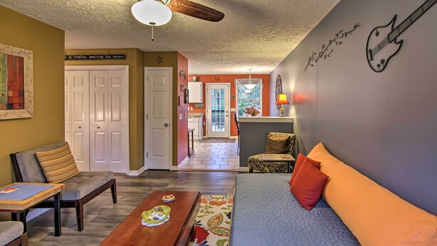 A living room with a sofa, a wooden coffee table, a ceiling fan, and a wall with guitar decorations. - Lively East Nashville Pad: Walk to Bars & Eateries (Nashville)