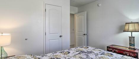 Een slaapkamer met een bed, een plafondventilator, een lamp en een dressoir.