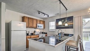 Une cuisine moderne dotée d’un îlot central, de meubles en bois, d’un réfrigérateur et d’un four à micro-ondes.
