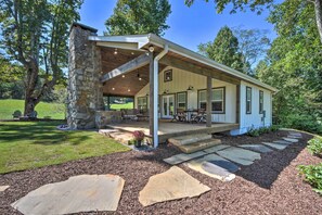 A stone-clad building with a covered porch, outdoor seating, and a stone pathway leading to the entrance.