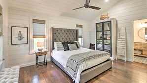 A bedroom with a tufted headboard, a bedside table with a lamp, a large bed with patterned bedding, a wardrobe with glass doors, and a wooden floor. - Blue Ridge Cottage: Modern Solace in the Mountains (Blue Ridge)