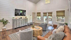 A spacious living room with a large TV, wooden flooring, and a cozy seating area with a sofa and armchairs. - Blue Ridge Cottage: Modern Solace in the Mountains (Blue Ridge)