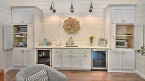 A kitchen with white cabinetry, a central island with a sink, and three pendant lights. - Blue Ridge Cottage: Modern Solace in the Mountains (Blue Ridge)