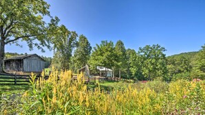 A rustic wooden cabin with a stone foundation, surrounded by a lush garden with various plants and flowers. - Blue Ridge Cottage: Modern Solace in the Mountains (Blue Ridge)