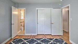 A hallway with a patterned rug, white doors, and a visible bathroom with a toilet and towel rack. - Spacious Retreat ~ 1 Mile to Augusta National! (Augusta)