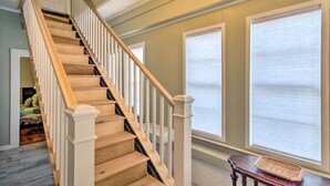 A staircase with wooden steps and white balusters, leading to a landing with large windows. - Pet-friendly Natchez Home: Walk to Downtown! (Natchez)