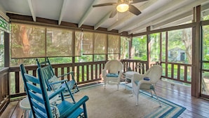 A covered porch with wooden railings, wicker furniture, and a ceiling fan. - Pet-friendly Natchez Home: Walk to Downtown! (Natchez)