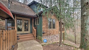 A wooden cabin with a front porch, a stone foundation, and a wooden fence. - Cozy Conyers Cabin w/ Fireplace & Pool Table! (Conyers)