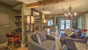 A spacious living room with a fireplace, a chandelier, and a comfortable seating area. - Cozy Conyers Cabin w/ Fireplace & Pool Table! (Conyers)