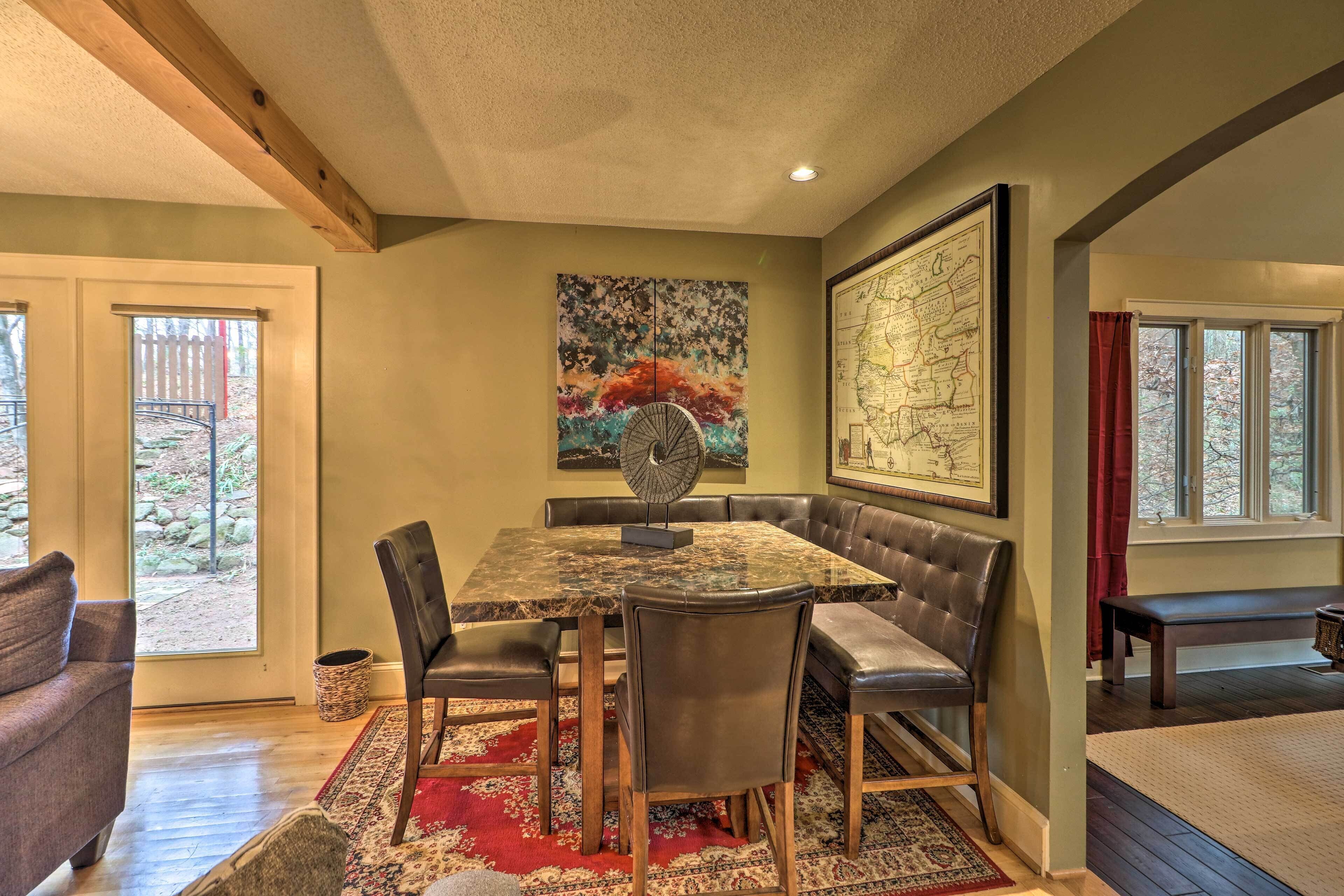A dining area with a marble table, leather chairs, and a red patterned rug.