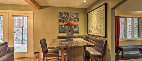 A dining area with a marble table, leather chairs, and a red patterned rug.