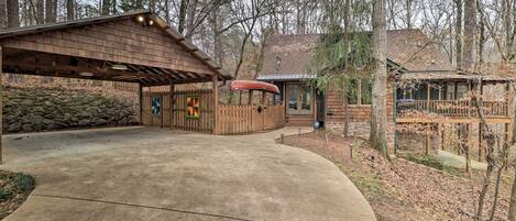 A rustic cabin with a covered porch, a canoe, and a stone wall.