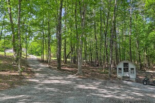A gravel path leading through a forest with a small cabin and a golf cart.
