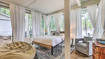 A bedroom with a bed, a bean bag, a chair, and a dresser.