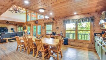 A spacious wooden cabin with a dining area, kitchen, and a loft bedroom.