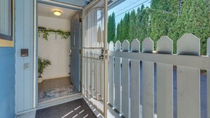 A wooden door with a glass panel, a white picket fence, and a view of tall trees in the background. - Bright & Airy Seattle Abode < 9 Mi to Space Needle (Seattle)