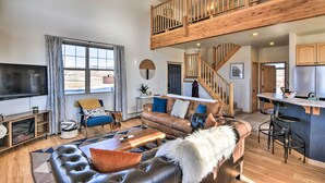 A spacious living room with a high ceiling, a wooden staircase, and a kitchen area. - 503 Mountain Loft w/ Views: 1 Mi to Dwtn Fairplay! (Fairplay)