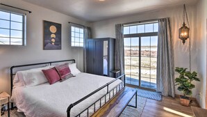A bedroom with a large bed, a wardrobe, a desk, and a view of the outdoors. - 503 Mountain Loft w/ Views: 1 Mi to Dwtn Fairplay! (Fairplay)