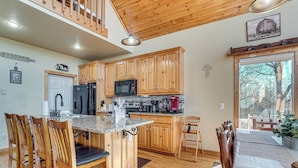 A kitchen with wooden cabinets, a granite countertop, and a dining area with wooden chairs and a table. - Pool, Hot Tub & Mountain Views: Cleveland Cabin (Cleveland)