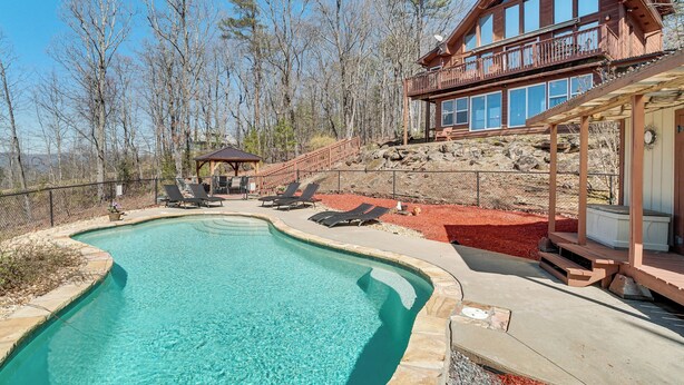 A wooden cabin with a large pool, lounge chairs, and a deck overlooking a forested area. - Pool, Hot Tub & Mountain Views: Cleveland Cabin (Cleveland)