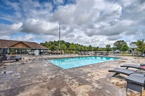 A swimming pool with lounge chairs and a fenced area, surrounded by trees and a building with a sloped roof. - Secluded Morganton Tiny Home w/ Grills! (Morganton)
