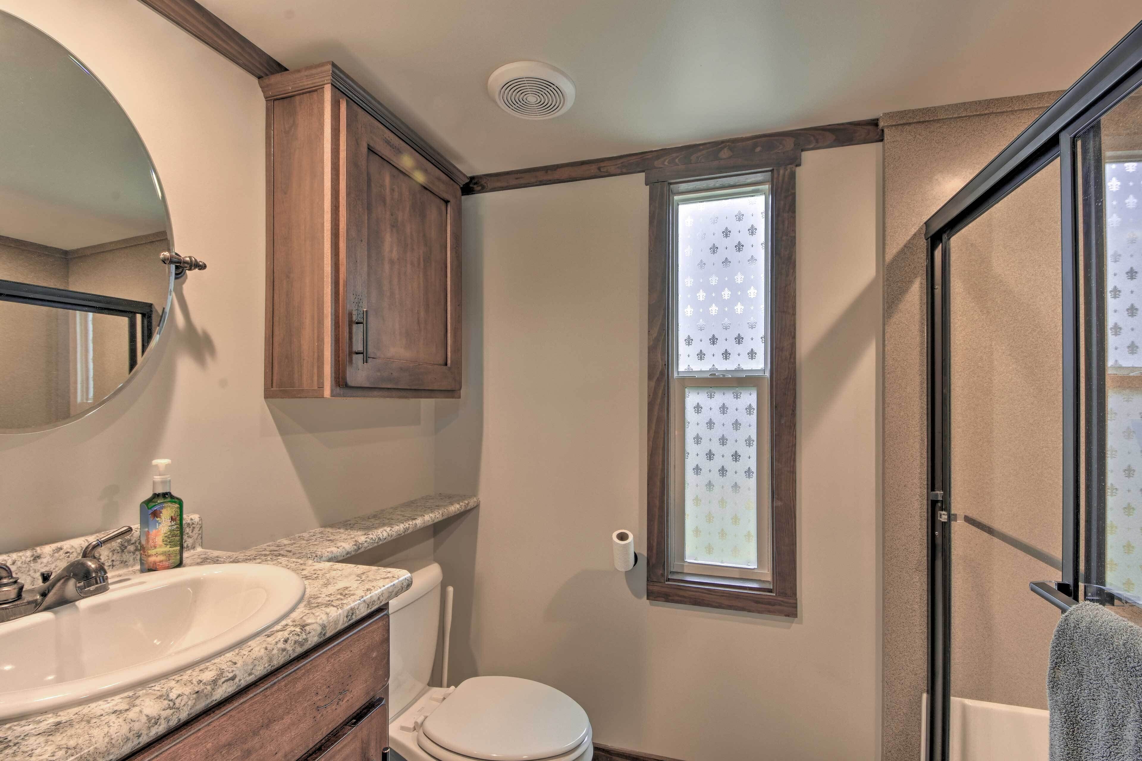 A bathroom with a double sink, toilet, and a window with patterned blinds.