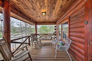 A wooden cabin with a porch featuring rocking chairs and a bench.