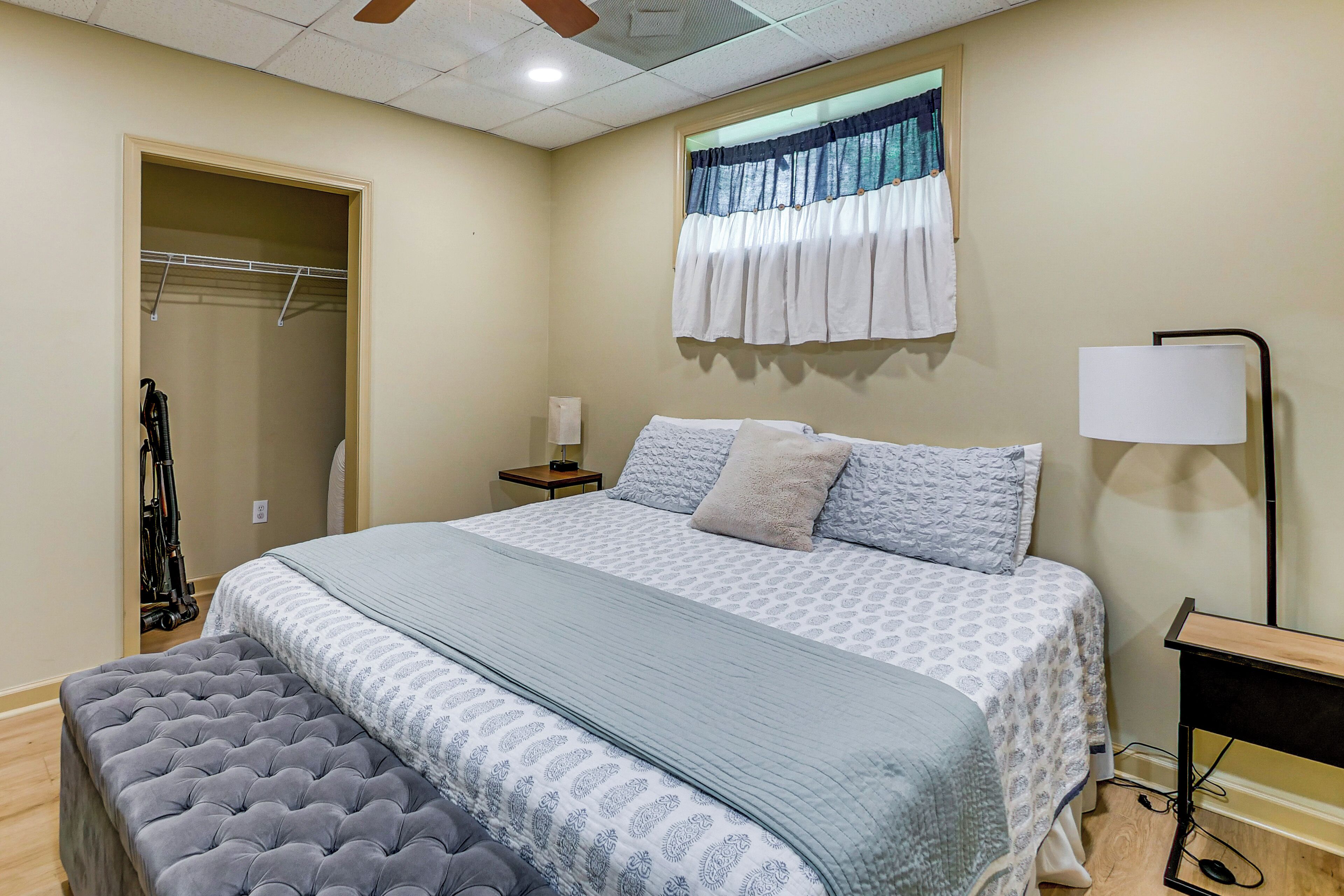 Ein Schlafzimmer mit Bett, Nachttisch, Lampe und einem Kleiderschrank mit Deckenventilator.