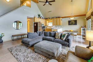 A spacious living room with a sectional sofa, ottoman, and a round mirror.