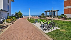 Un percorso che conduce a un edificio con vista sul mare, un gazebo e biciclette parcheggiate.