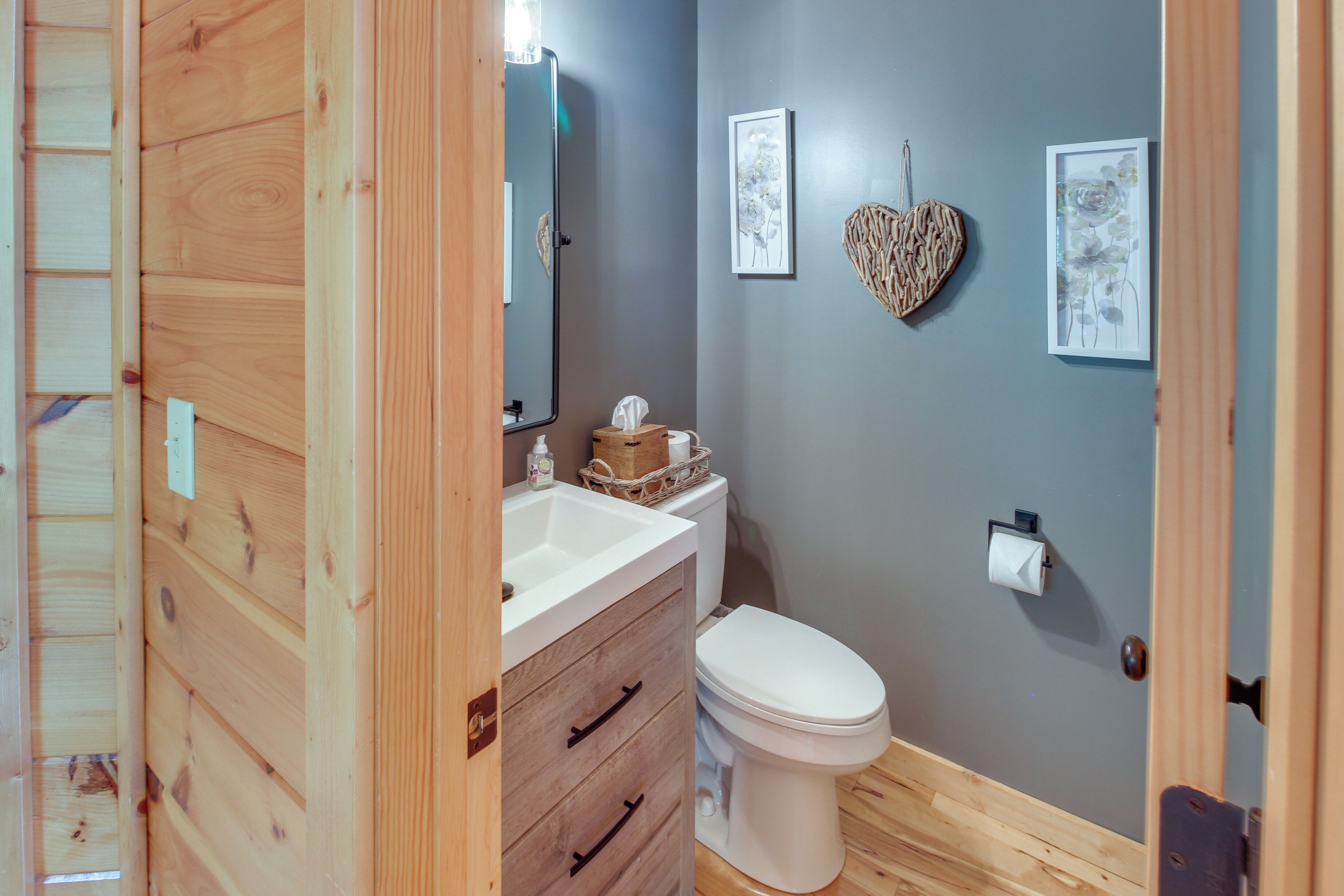 A bathroom with a wooden vanity, a white toilet, and a mirror.