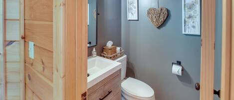 A bathroom with a wooden vanity, a white toilet, and a mirror.