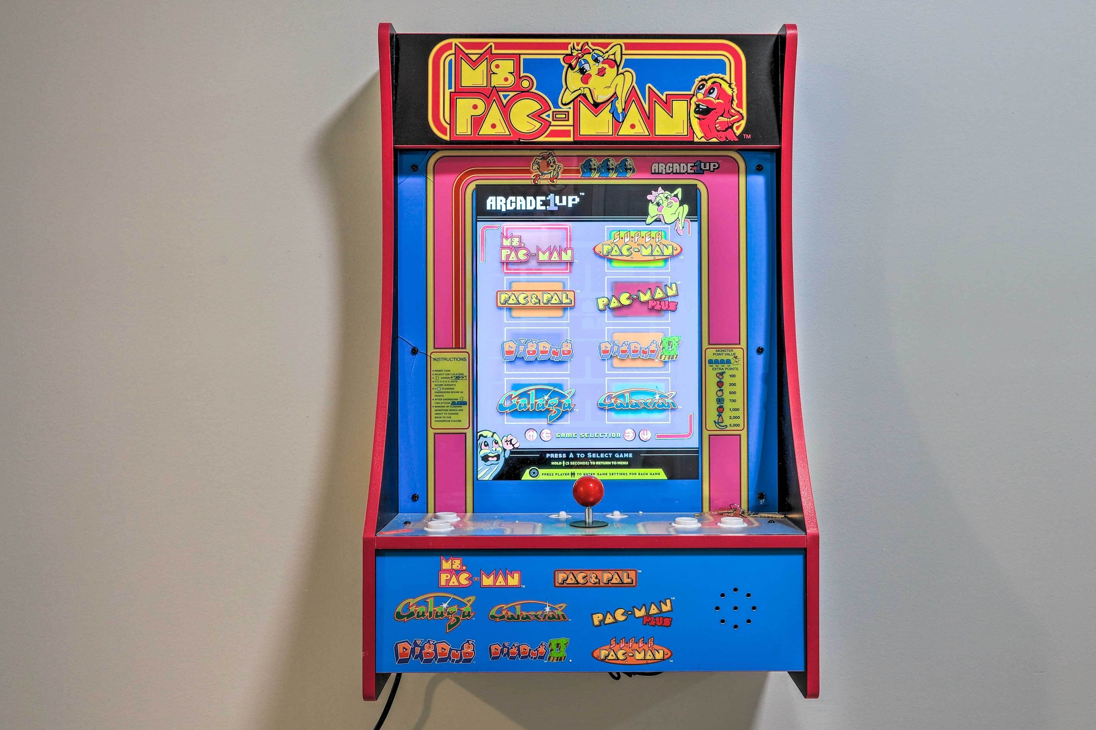 A Pac-Man arcade game machine with colorful graphics and a selection of games.