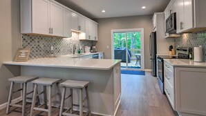 Una cocina moderna con armarios blancos, una isla grande con taburetes y vistas al exterior.