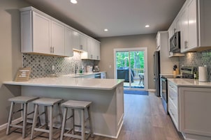 Una cocina moderna con armarios blancos, una isla grande con taburetes y vistas al exterior.