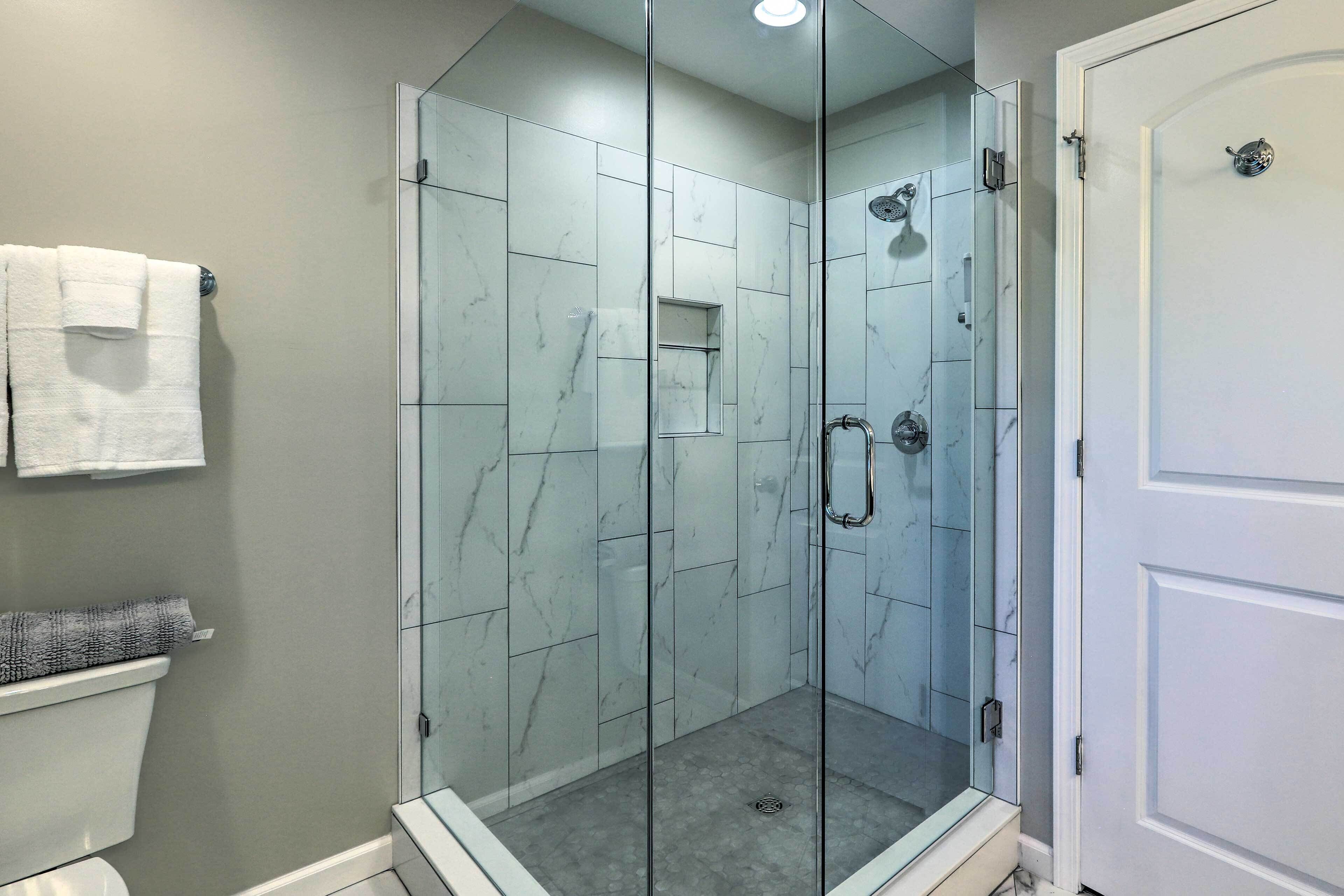 A modern bathroom with a glass-enclosed shower, a toilet, and a towel rack.
