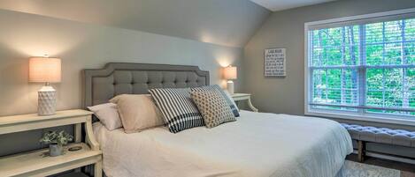 Una camera da letto con un letto grande, due comodini, una ventola a soffitto e una finestra con vista su del verde.