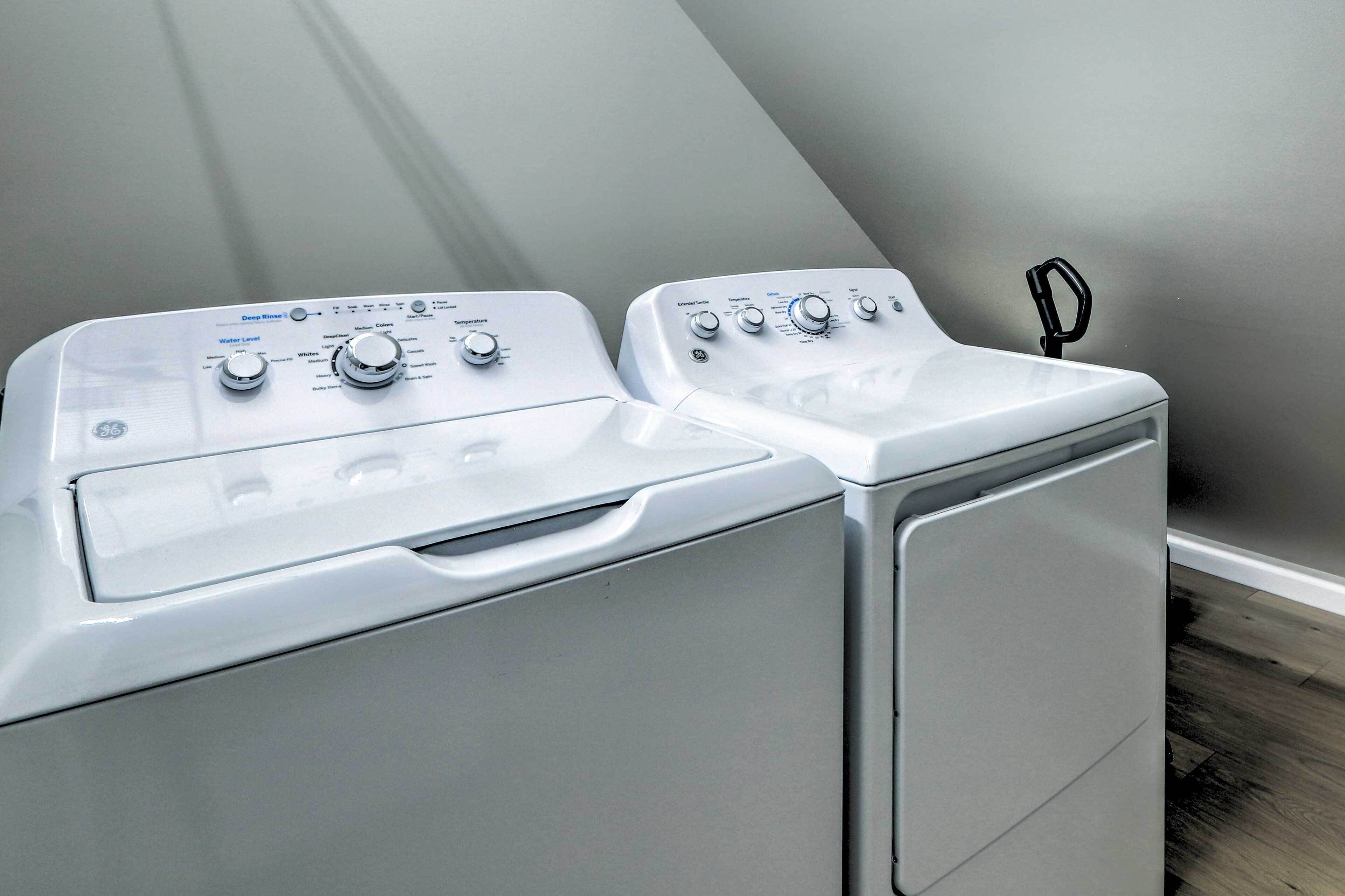 A front view of a front-loading white washer and dryer unit with control knobs and a water level indicator.