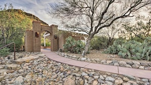 Un jardín desértico con un arco de ladrillo, plantas de cactus y un camino pavimentado.