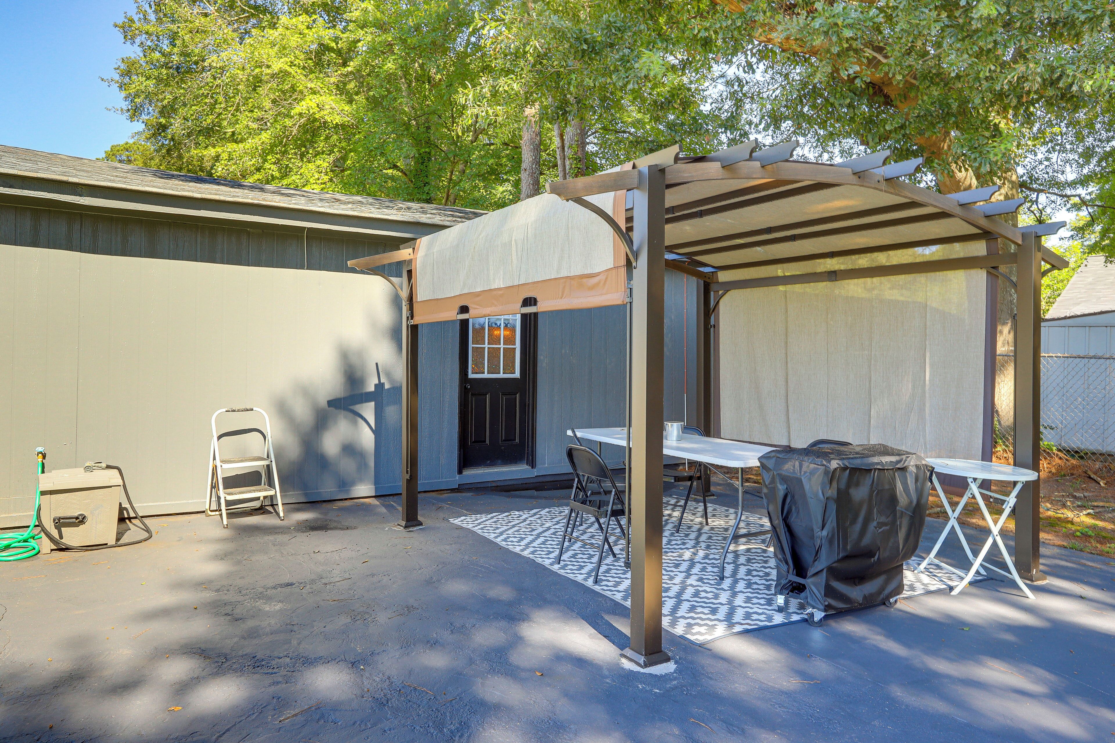 A covered patio area with a table and chairs, a folding chair, and a covered grill.