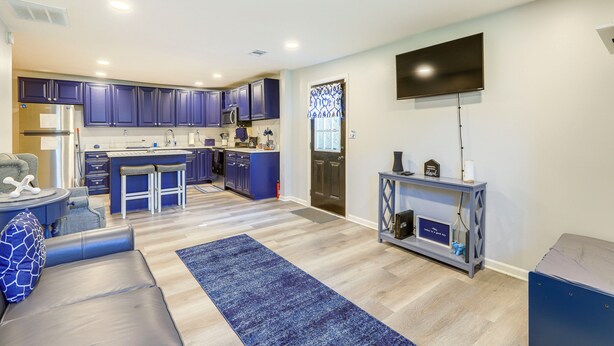 A modern kitchen with blue cabinets, a central island, and a flat-screen TV mounted on the wall. - Conyers Vacation Rental w/ Pool: 5 Mi to Olde Town (Conyers)