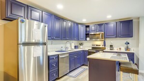 A modern kitchen with stainless steel appliances, blue cabinets, and a central island. - Conyers Vacation Rental w/ Pool: 5 Mi to Olde Town (Conyers)